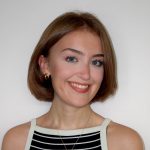 headshot of a woman with light brown, chin-length hair wearing a black and white tanktop