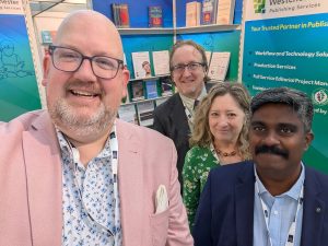 A group of colleagues standing inside a trade show booth for Westchester Publishing Services and Westchester Education