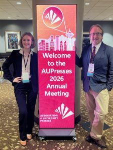 woman and man flanking a roll up banner for the 2026 Association of University Presses Conference